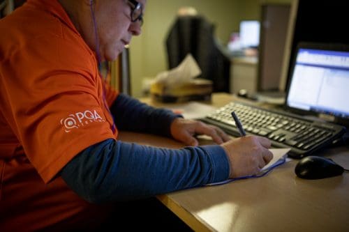 Software tester write notes while wearing headphones